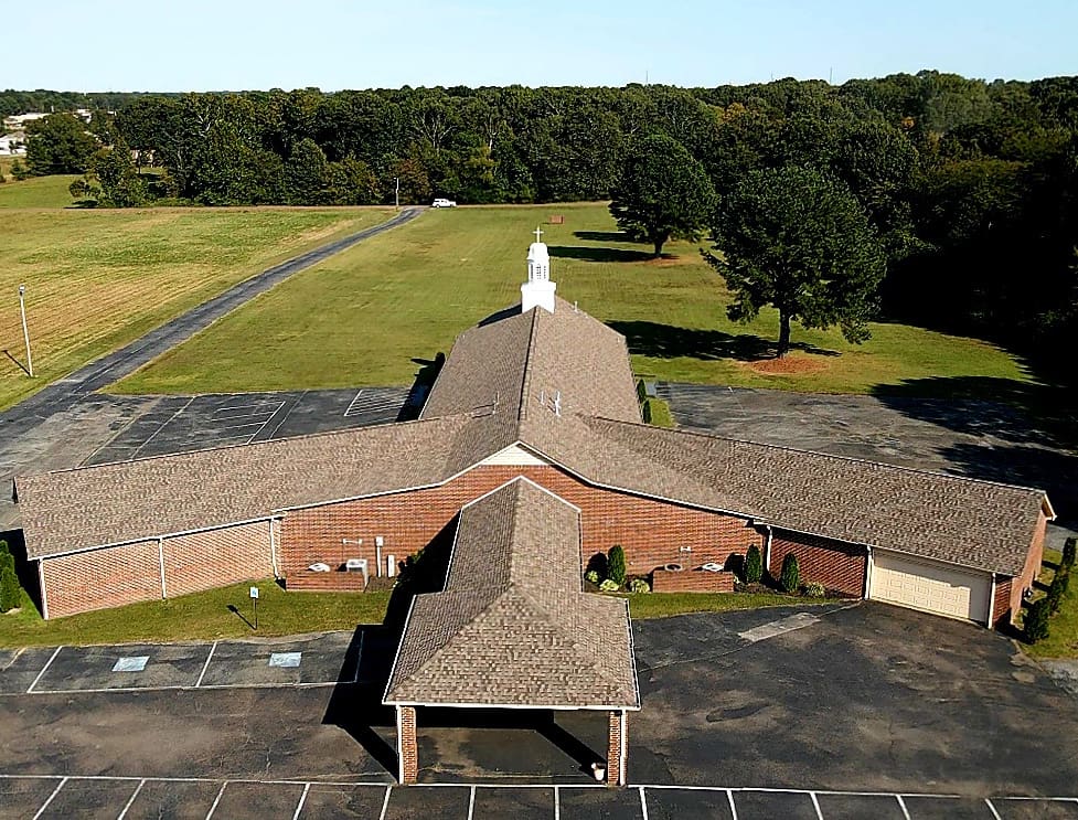 An aerial view of a church with trees in the background.